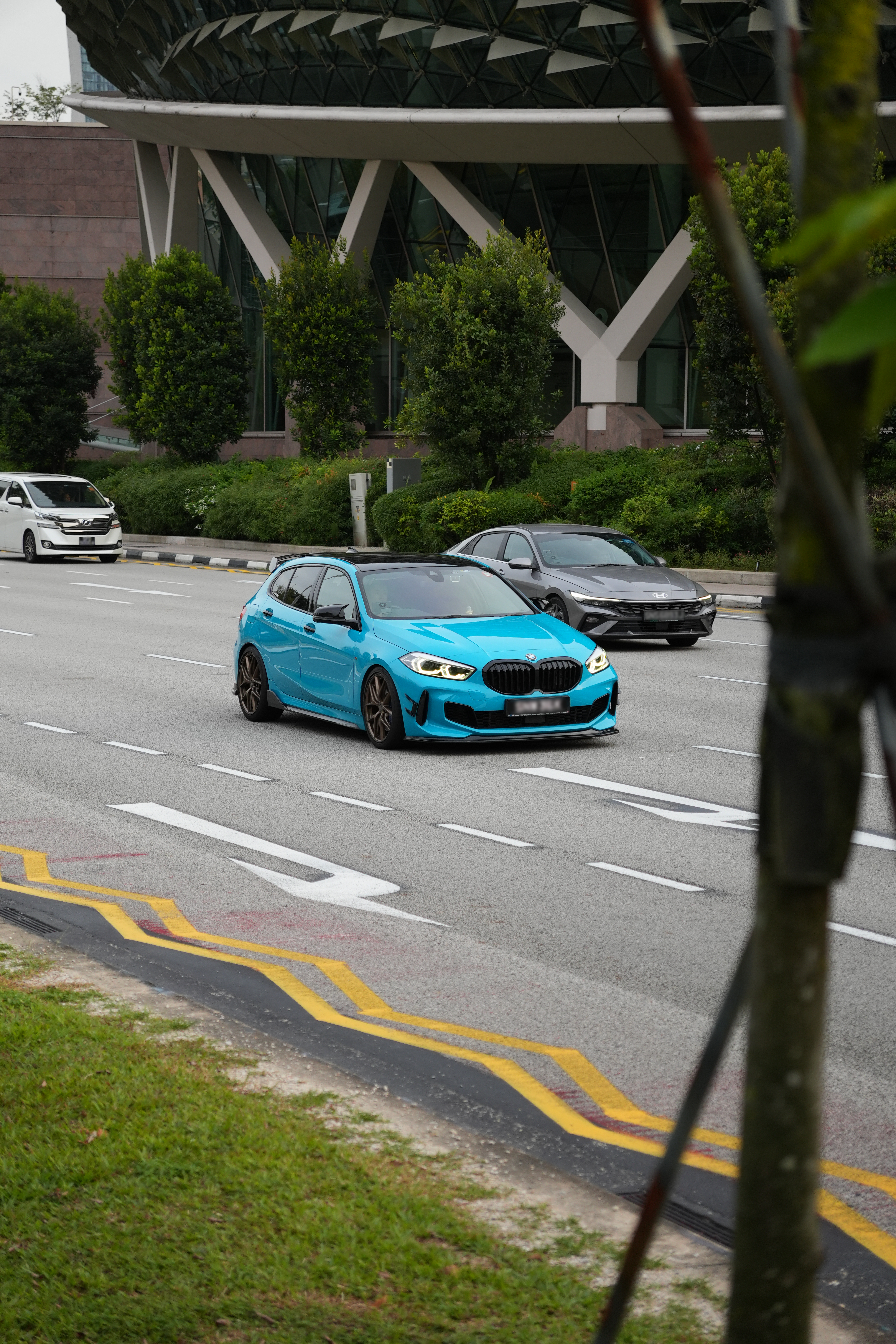 Blue BMW on the street passing by the Esplanada in Singapore