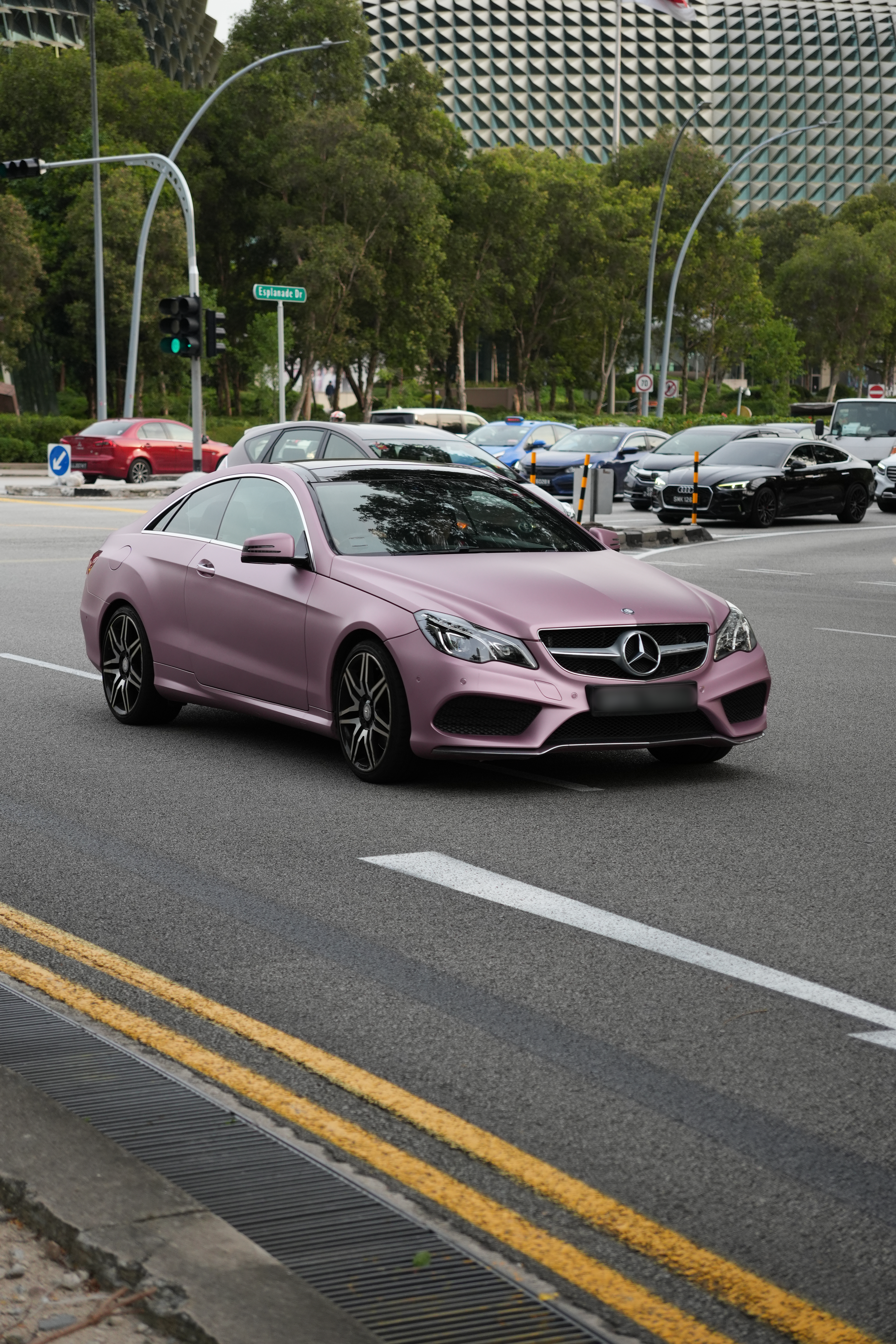 Pink Mercedes Benz on the street passing by the Esplanada in Singapore