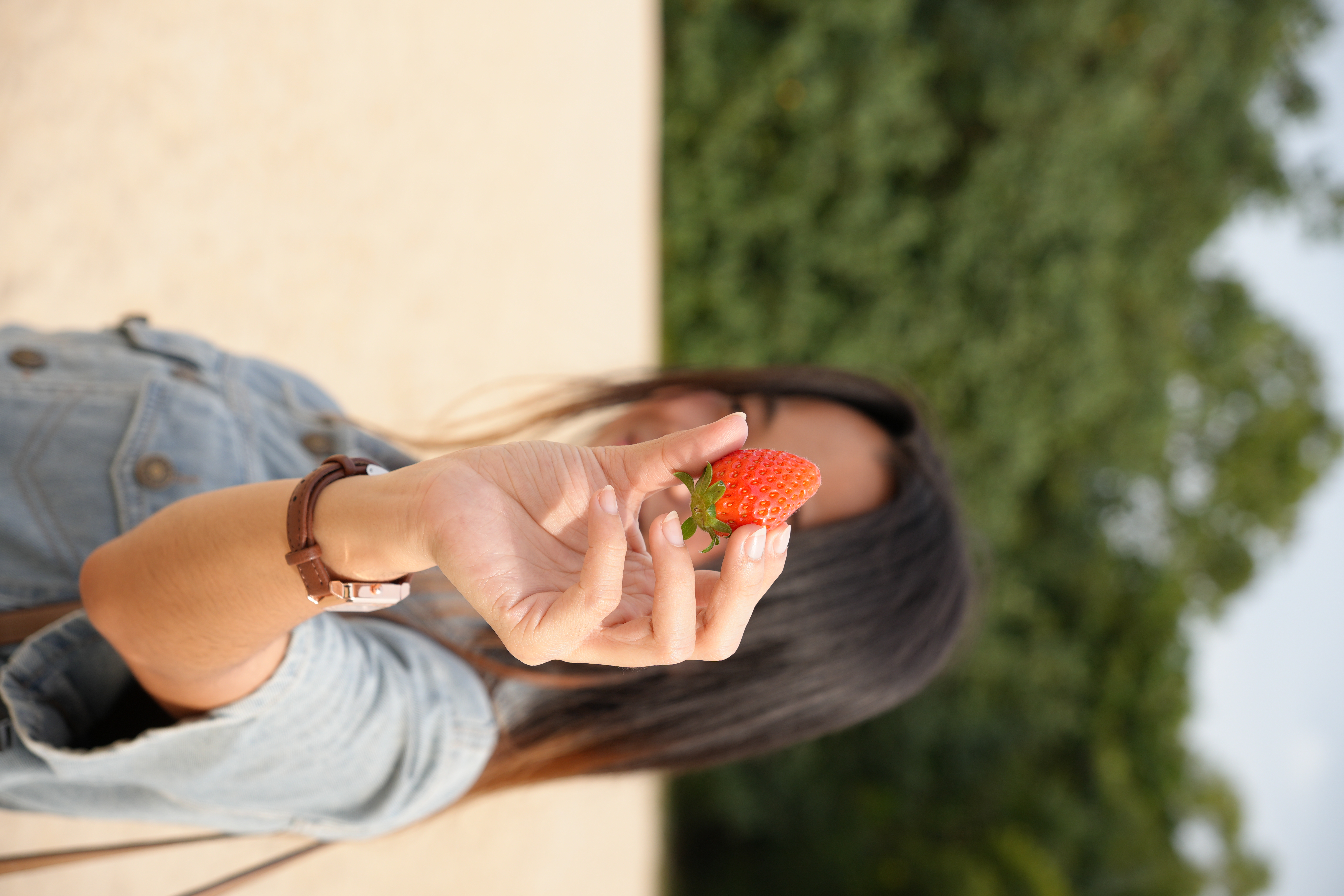 Image of model hiding her face behind a strawberry